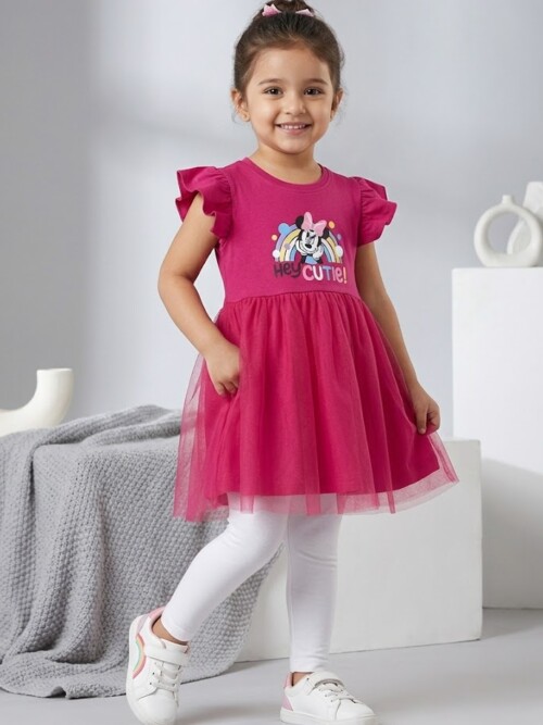 Cute little girl smiling and posing in Bachaa Squad pink Minnie Mouse summer dress with white leggings in a photo studioCute little girl smiling and posing in Bachaa Squad pink Minnie Mouse summer dress with white leggings in a photo studio