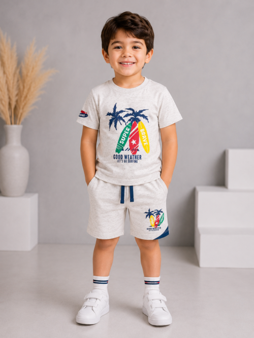 Cute little boy wearing oatmeal color surf print t-shirt with matching shorts in a grey and white studio background, soft cotton summer outfit for kids